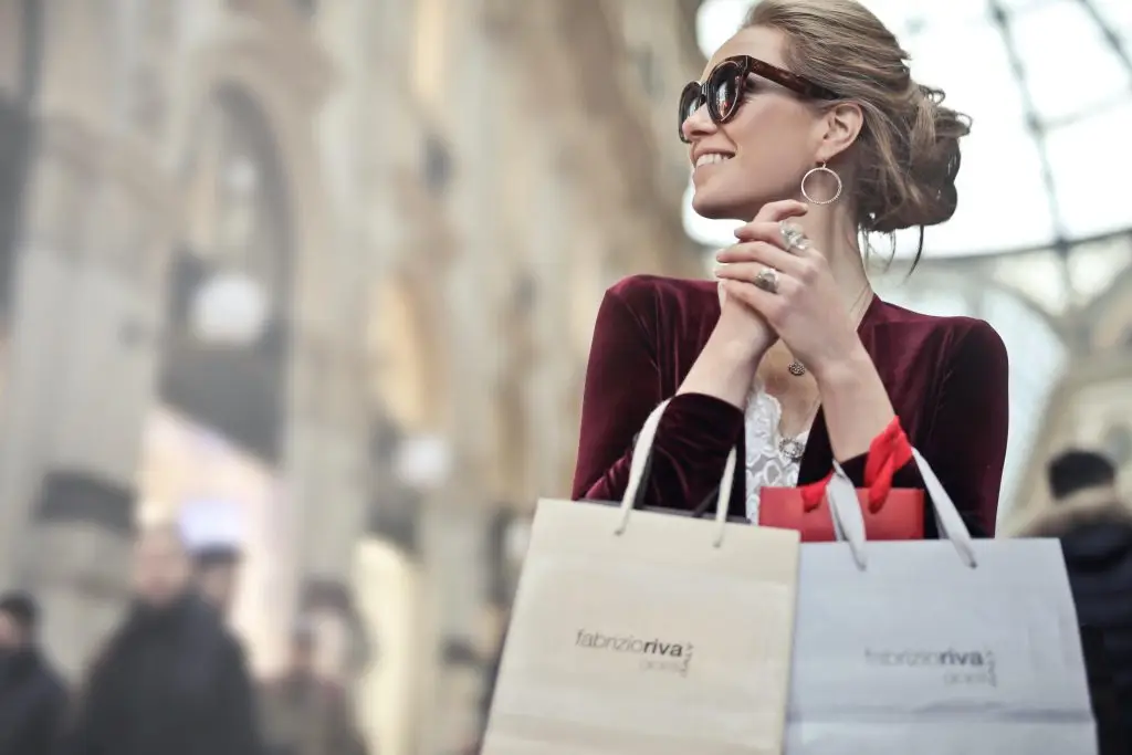Woman shopping in luxury mall, smiling with shopping bags – symbolizing joy, empowerment, and confidence